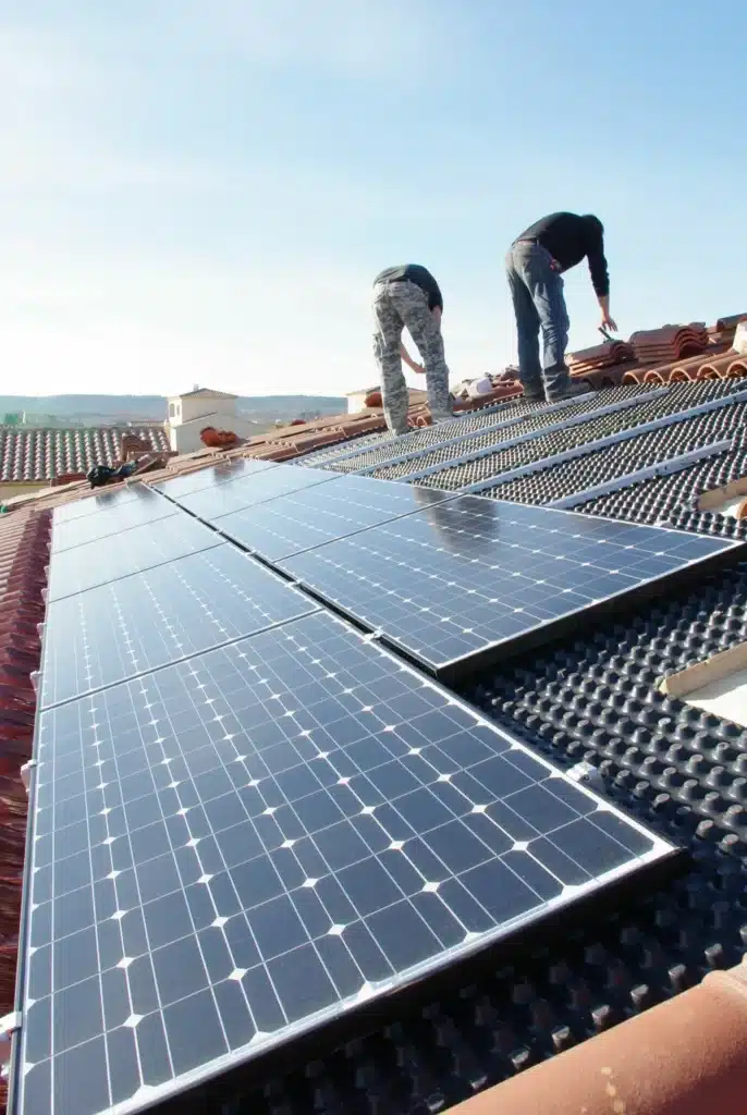 Ouvriers en train d'installer des panneaux photovoltaïques sur le toit d'une maison.